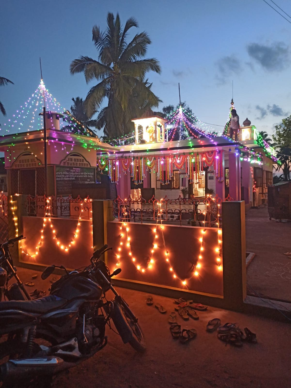 The temple's exterior at dusk, string lights along the walls and roofline