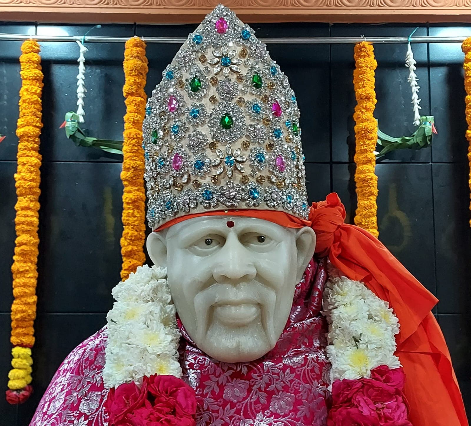 The murti's face, adorned with a jeweled crown, seen up close